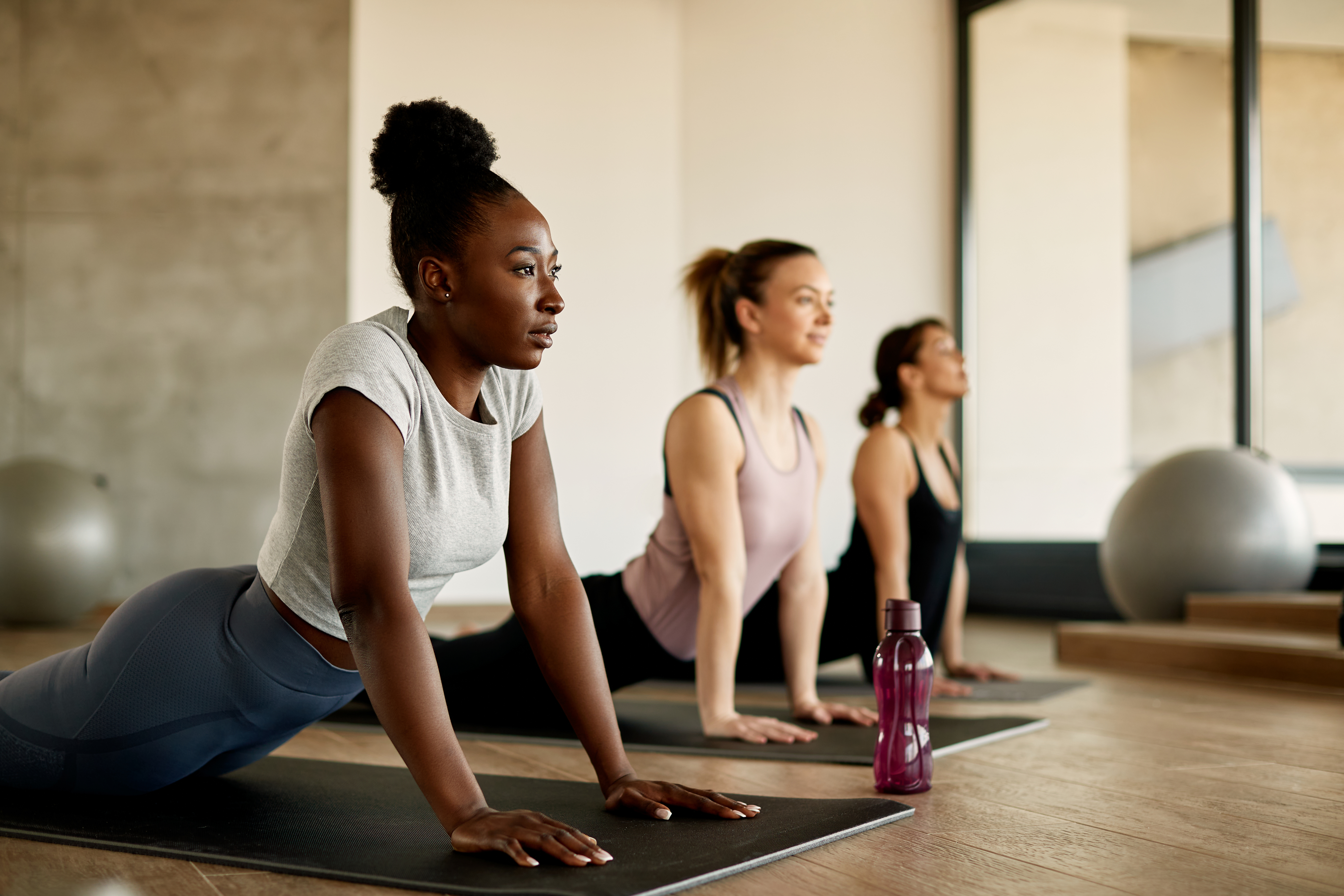 Three women in a yoga studio in upward-facing dog position